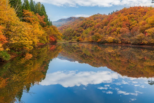 紅葉した山々が映る湖面の秋の空