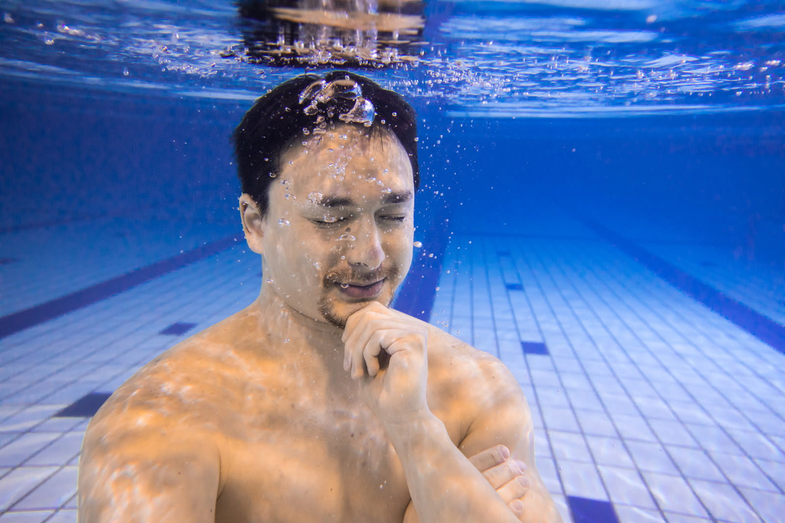 屋内プールの水中で瞑想する男性［モデル：Max_Ezaki］