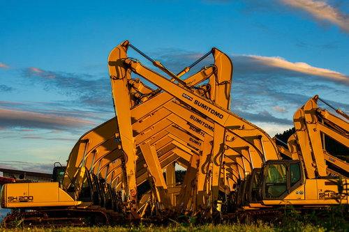 夕焼けの中でシンクロするショベルカーと建設機械
