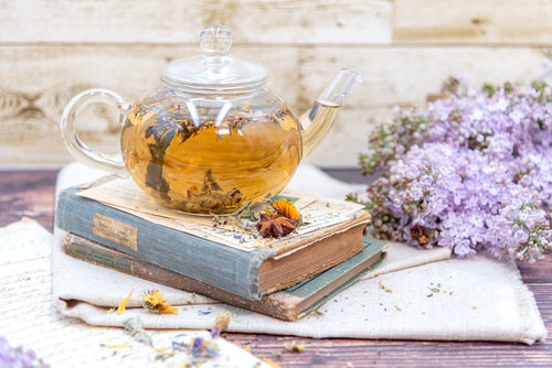 洋書の上に置かれたティーポットとライラックの花