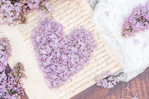 白い便箋に淡い紫のライラックの花で作るハート