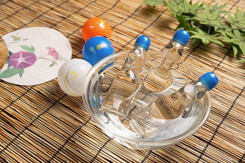 竹かごに並ぶ水風船とラムネ、うちわの夏祭り納涼グッズ