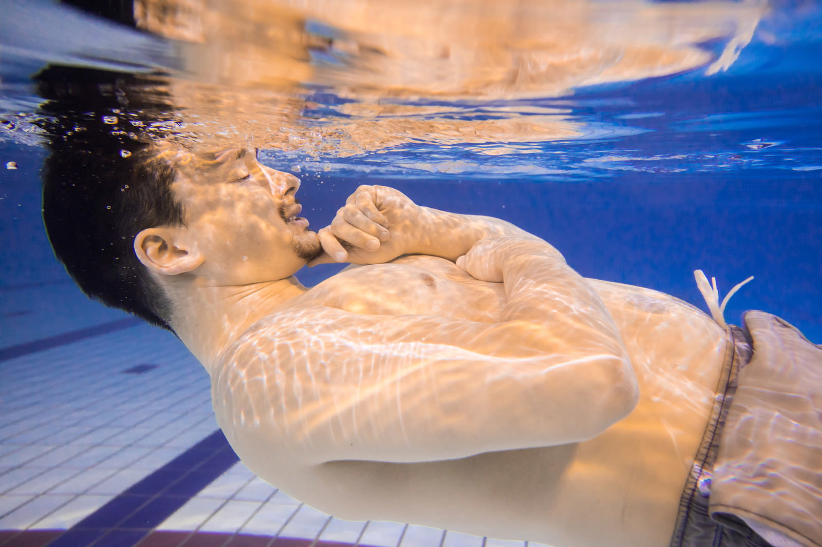 プールの水中で考え込むような表情をしている男性［モデル：Max_Ezaki］