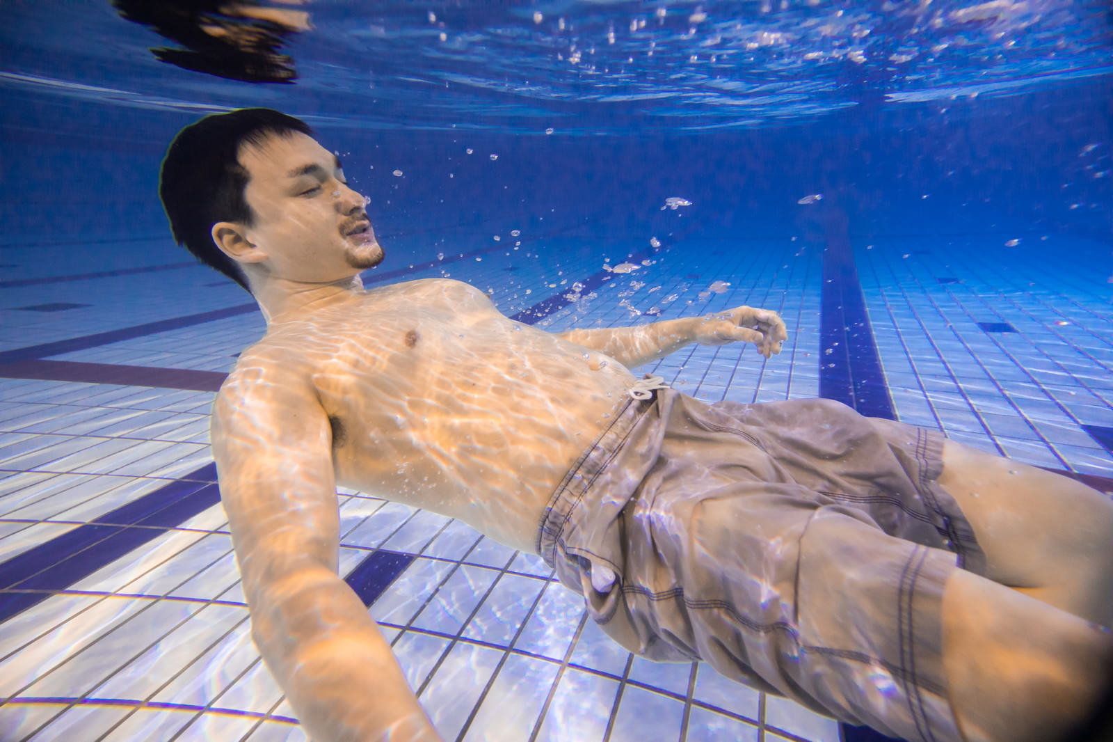 プールの水中で息を止めて浮いている男性［モデル：Max_Ezaki］