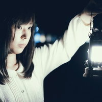 夜の暗闇でランタンを灯して歩く白い服の女性の写真