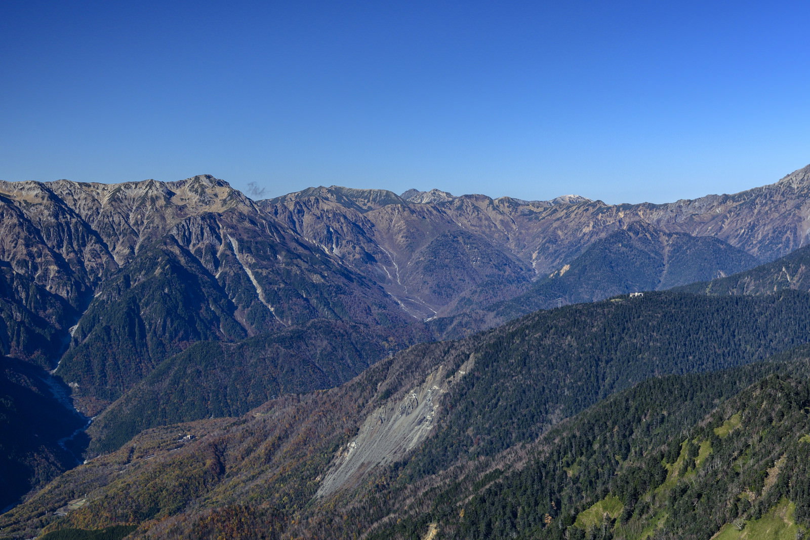 青空の下に連なる裏銀座方面の山々と紅葉した山肌が見える晩秋の風景