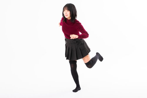 赤いセーターと黒いスカートで片足を上げてダッシュで駆け出す女性