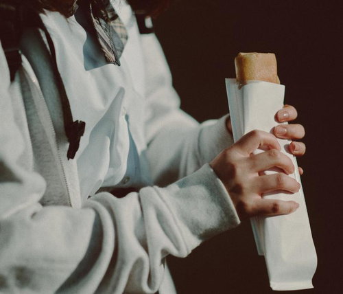 制服姿の女子高生が手に持つお菓子のパッケージ