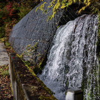 岩肌から流れ落ちる水が滝をなす国道158号線の写真