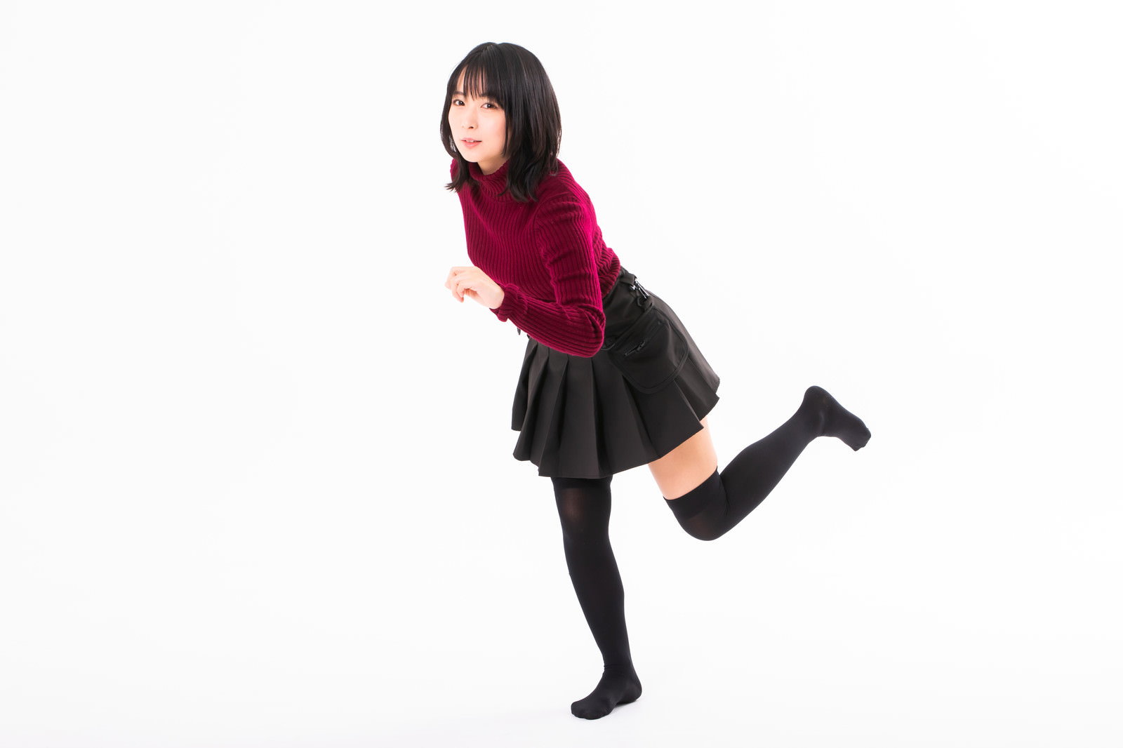 赤いトップスと黒いスカートを着た女性が走り出すポーズをする［モデル：にゃるる］