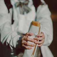 持ち帰りで買ったサンドイッチを食べ歩く女子高生の写真