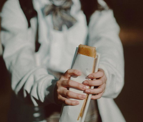 持ち帰りで買ったサンドイッチを食べ歩く女子高生