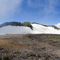 大雪山の旭岳に残る大きな雪の壁と青空の風景の写真