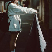 放課後の通学路でジーンズを掲げる女子高生の写真