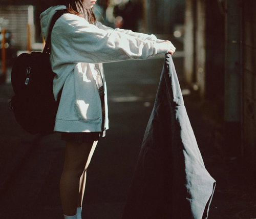 放課後の通学路でジーンズを掲げる女子高生