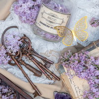 紫のライラックと鍵が散らばるアンティークなトランクケースの写真