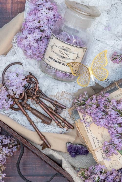 紫のライラックと鍵が散らばるアンティークなトランクケース