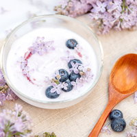 ライラックの花に囲まれたブルーベリーヨーグルトの写真