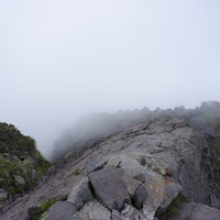 ガスに包まれた日光白根山山頂の岩稜帯と稜線の写真