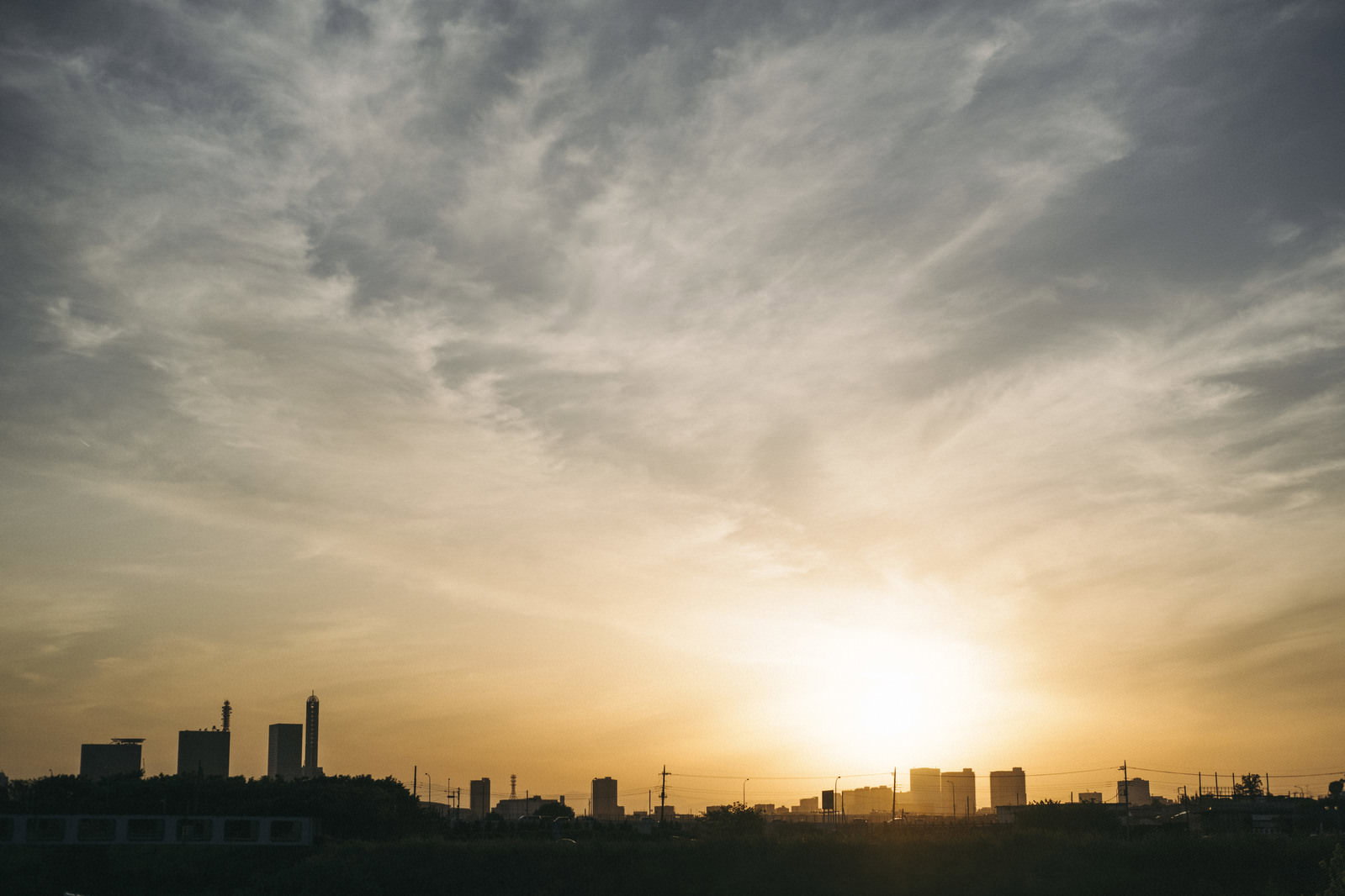 オレンジ色の夕焼け空に沈む太陽とビル群のシルエット