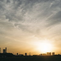 ビル街に沈む夕日のシルエット、オレンジ色に染まる都市風景の写真