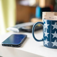 星柄のマグにドリップコーヒーを入れてスマホと一緒に机に置くの写真