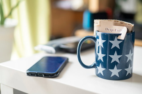 星柄のマグにドリップコーヒーを入れてスマホと一緒に机に置く