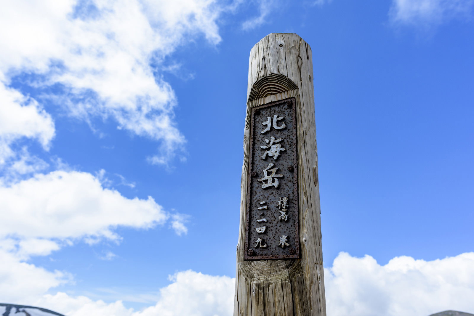 青空を背景に立つ大雪山北海岳の木製標柱