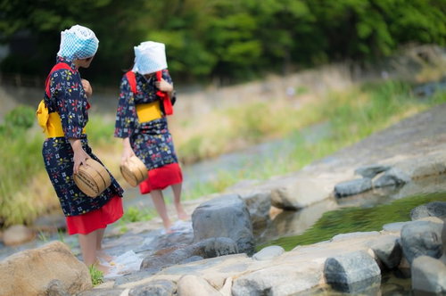 赤い腰巻きと黄色い帯をつけた姉さんが川辺でフミフミ洗濯（足踏み洗濯）