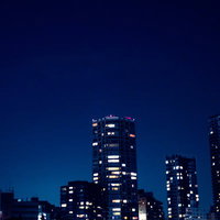 部屋の明かりがまばらな高層マンションの夜景の写真