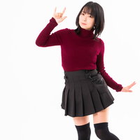 赤いタートルネックではしゃぐ女性のハンドサインの写真