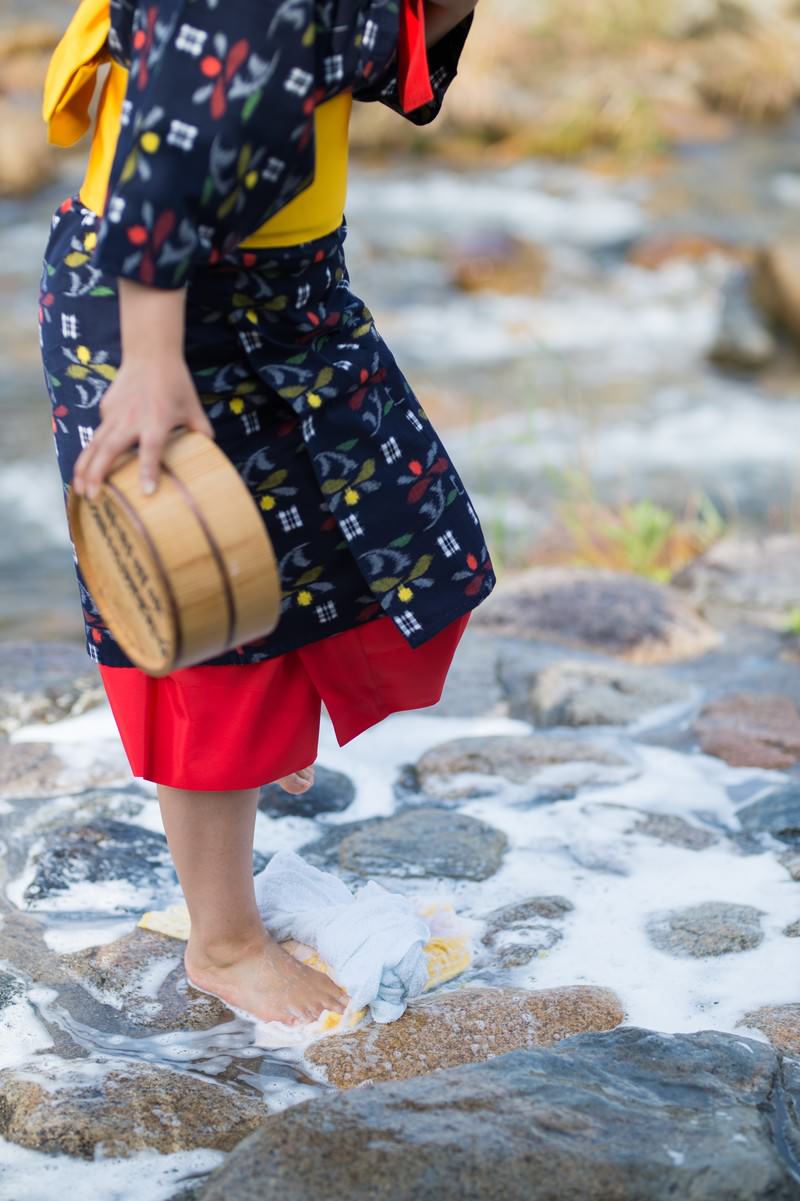 Woman in a star-patterned kimono doing foot-stomping laundry in the river
