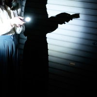 懐中電灯ひとつで夜を探索するシルエットの写真