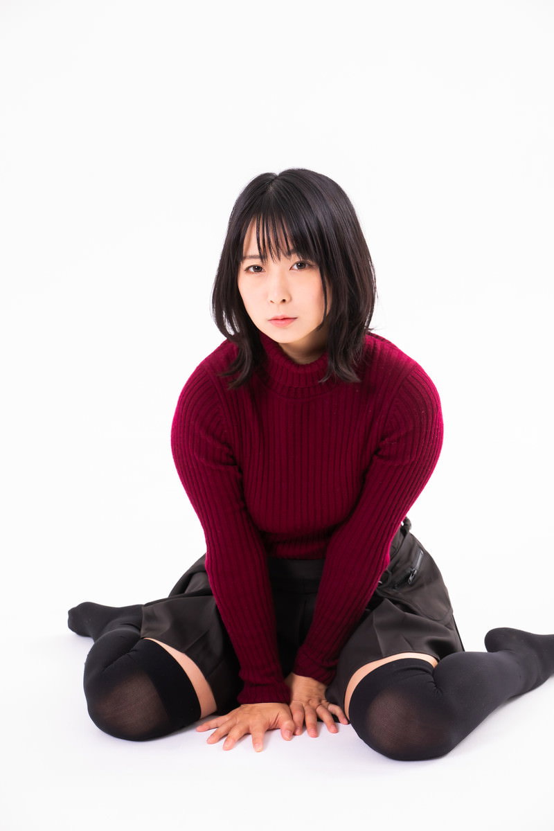深い赤色のニットを着た女性が床にペタンと座り込んでいる［モデル：にゃるる］