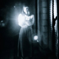 懐中電灯で正面を照らす女性の姿（ホラー素材）の写真