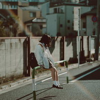 女子高生が通学路の柵に腰掛けている姿の写真