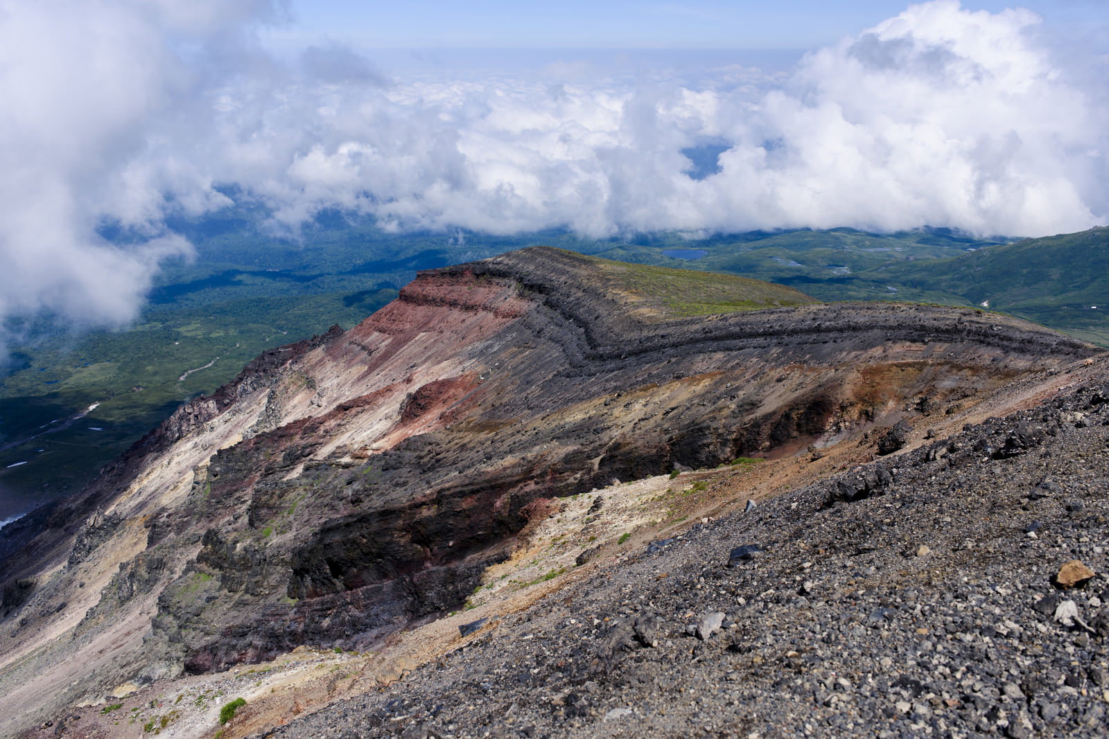 旭岳の荒々しい岩肌と険しい崖、背景に雲に包まれた山々