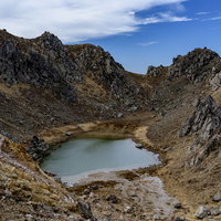 焼岳山頂の火山湖と荒々しい火口の写真