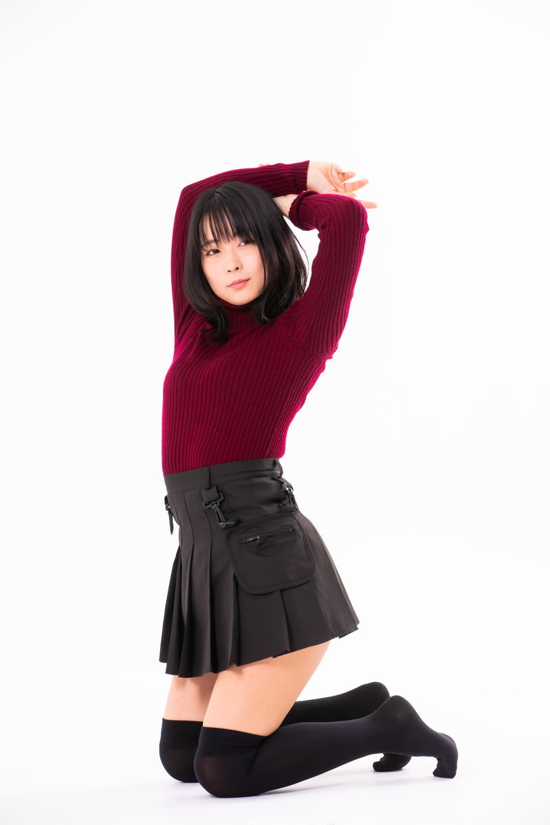 赤いトップスを着た女性が膝をついて両手を上に伸ばすポーズ［モデル：にゃるる］
