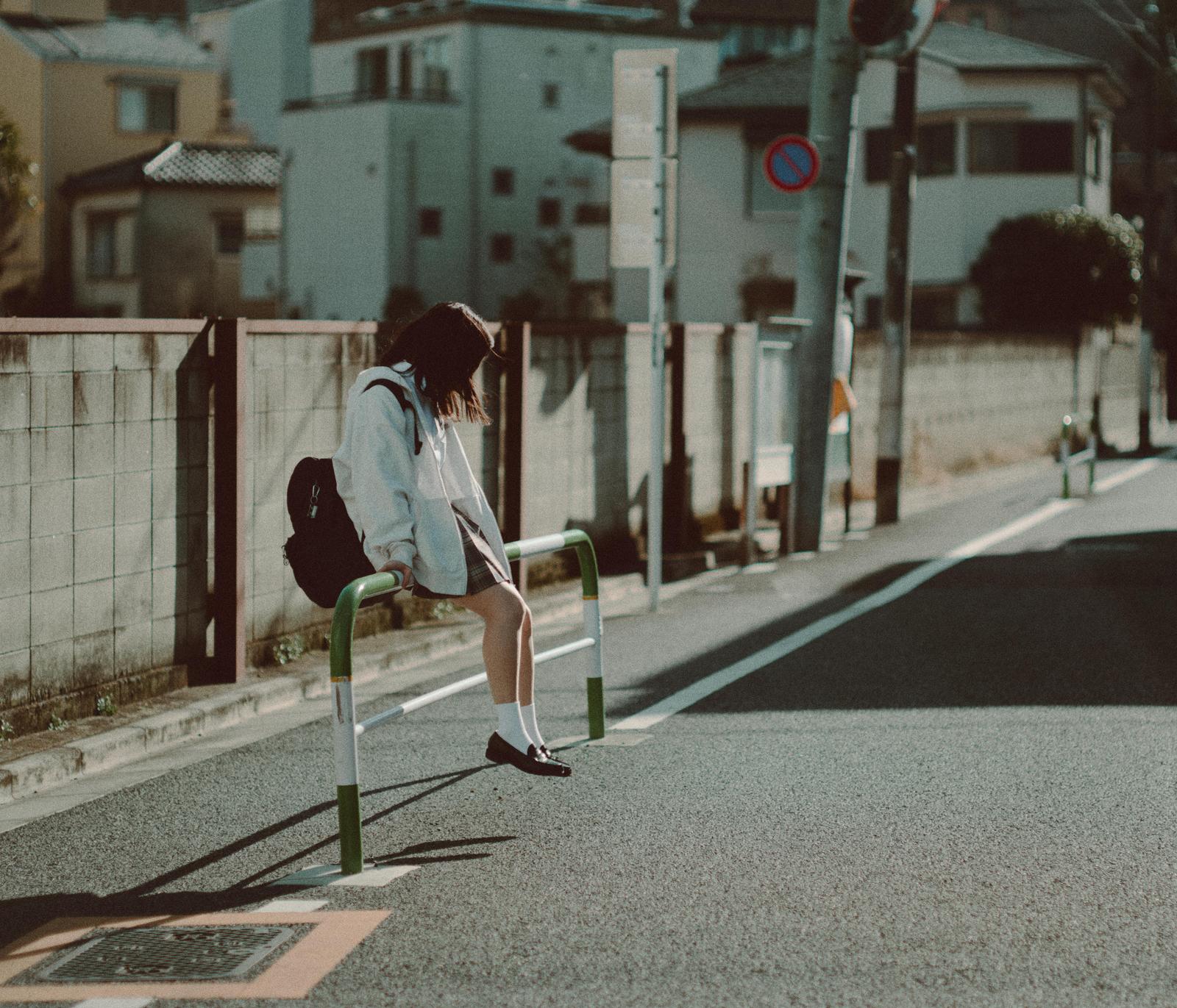 路上で項垂れるグレーのパーカーを着た女子高生