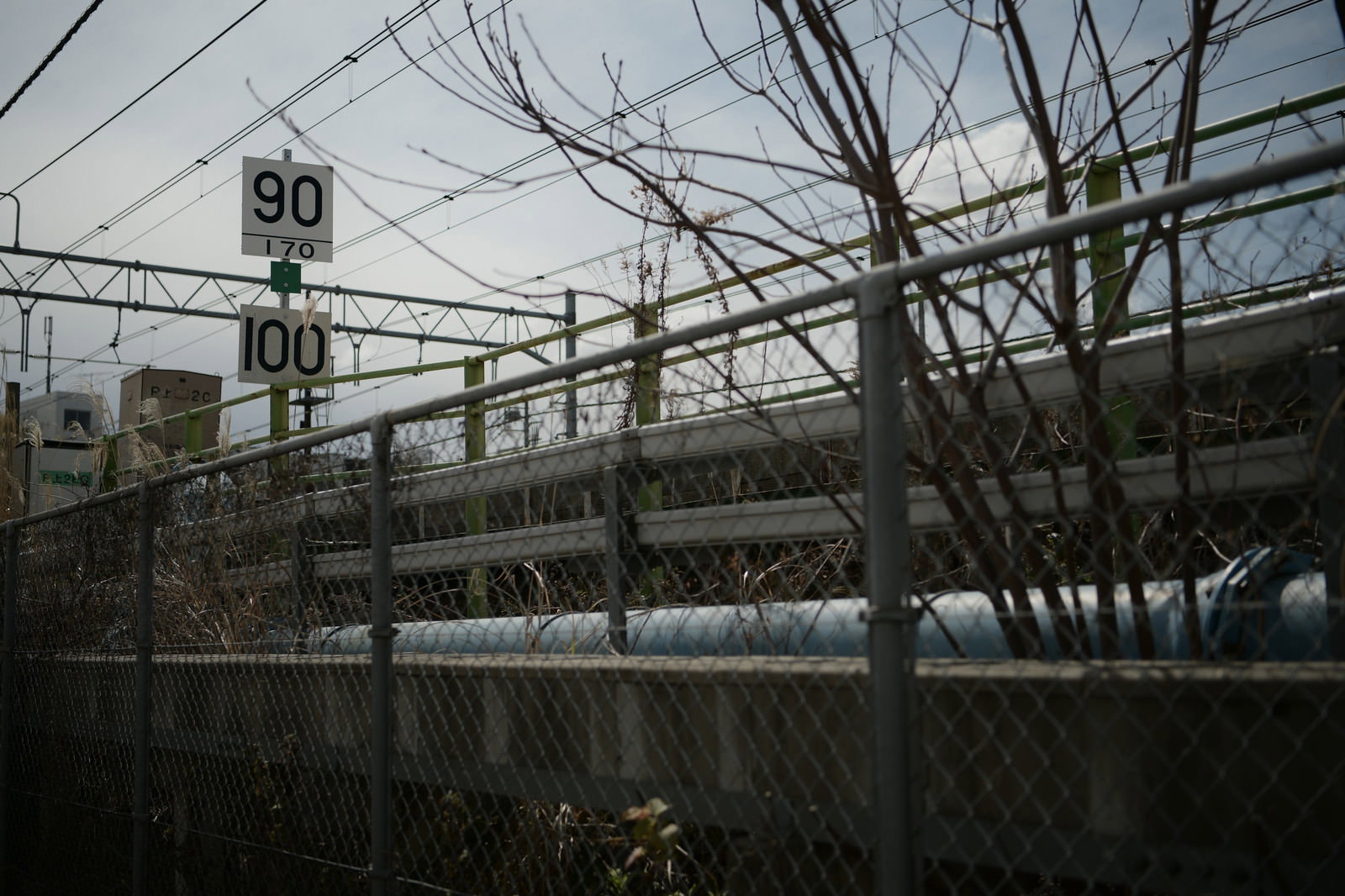 金網フェンス越しに見える線路と電線、看板のある都市風景