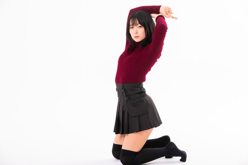 床に膝をついて両手を上げるストレッチポーズをとる女性