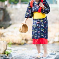 吉井川の側で温泉を使って足踏み洗濯する着物姿の女性の写真