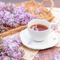 洋書に散らしたライラックとティーカップの紅茶の写真