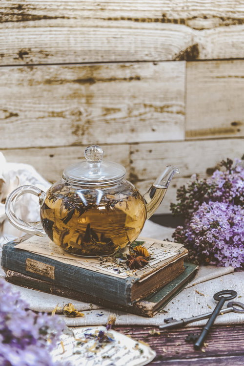 木製テーブルに置かれた洋書とハーブティー