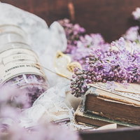 縛られた洋書の上に置いたライラックと香水瓶の写真