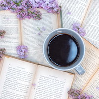 洋書に囲まれたコーヒーカップと紫のライラックの写真