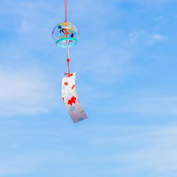 夏の象徴、青空に揺れる風鈴と短冊の涼感を映した風情の写真