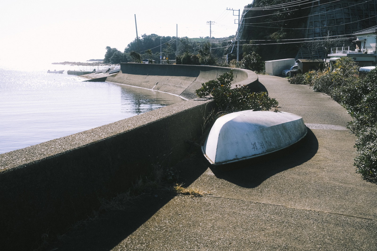 三浦半島の港町の道端、海岸沿いのコンクリートに置かれた白いボート
