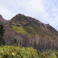 焼岳山頂を目指す登山道の新緑と岩山の風景の写真
